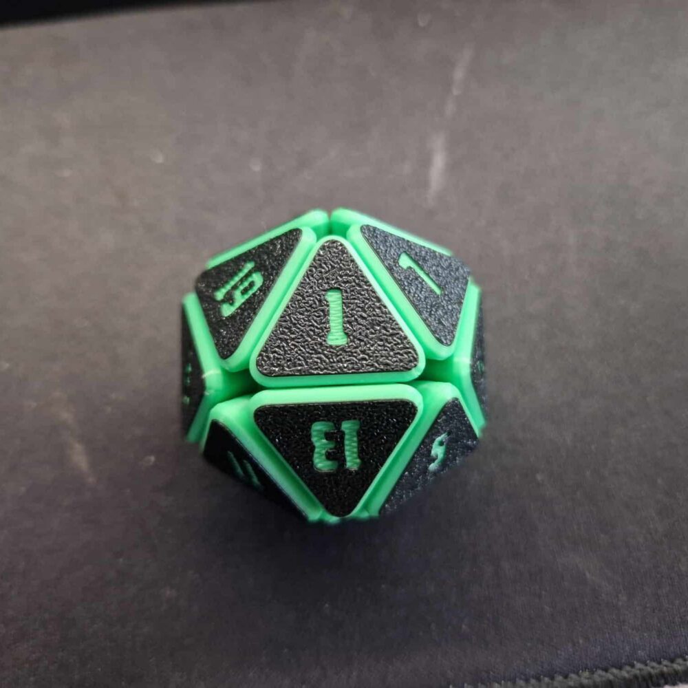 Grüner Squishy D20 Fidget Würfel mit schwarzen Flächen und grünen Zahlen, liegend auf einer dunklen Würfelmatte – ideal für D&D und Tabletop-Runden.