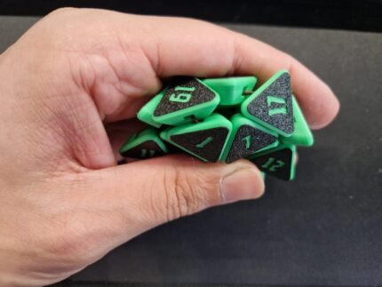Hand drückt einen grünen Squishy D20 Fidget Würfel mit schwarzen Flächen und grünen Zahlen zusammen – zerdrückbarer Würfel für D&D und Tabletop.