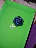 Blauer Squishy D20 Fidget Würfel mit funkelnden Reflexen, liegend auf einer grünen Würfelmatte – besonderes Zubehör für Tabletop und D&D.